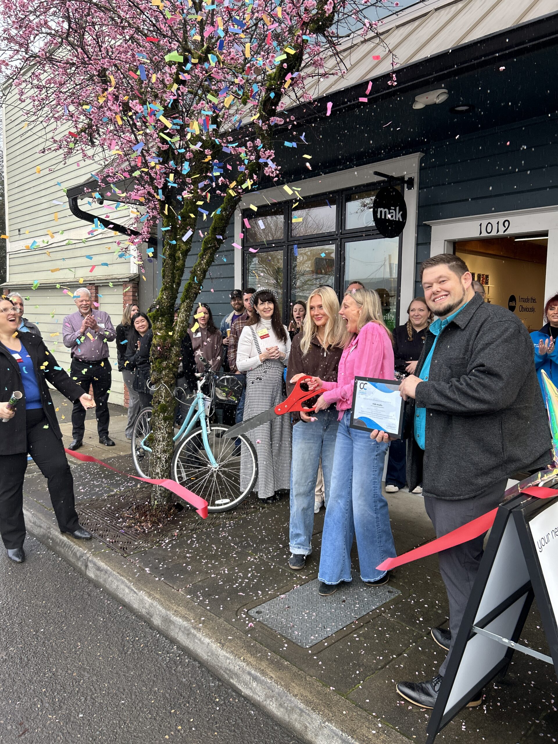 Laurie and Sydney stand with the Oregon City Chamber of Commerce in front of māk during the ribbon‑cutting ceremony. Confetti fills the air as the group smiles and celebrates the grand opening of the creative studio.